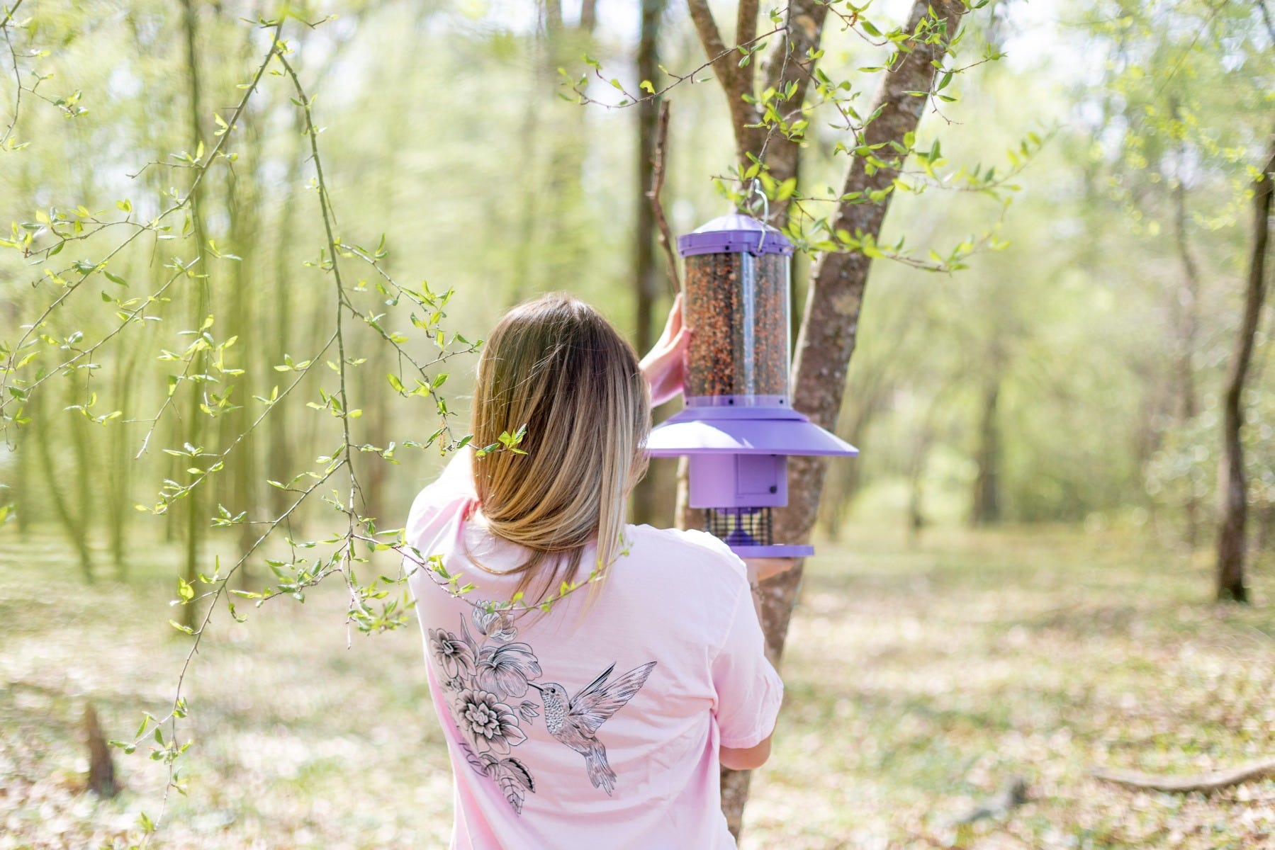 girl hanging purple Wingscapes Autofeeder wearing a pink Wingscapes logo t-shirt
